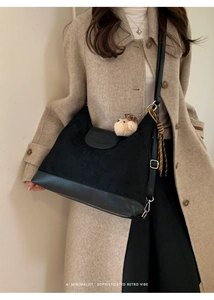 Detail of black suede tote bag with leather bottom and decorative bear keychain