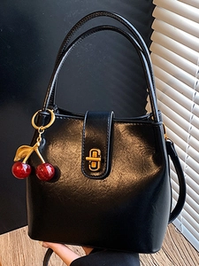Minimalist black bucket handbag with cherry charm and gold hardware clasp