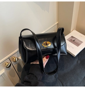 Vue détaillée du sac en simili cuir noir brillant avec un élégant fermoir rotatif ovale doré