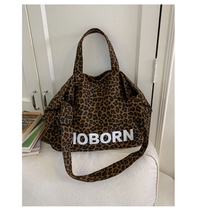 Close-up of leopard print tote bag with white MOBORN text and wide shoulder strap