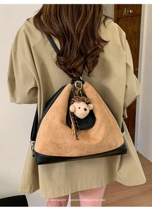 Detail of vintage two-tone tote bag with suede texture and cute teddy bear charm accessory