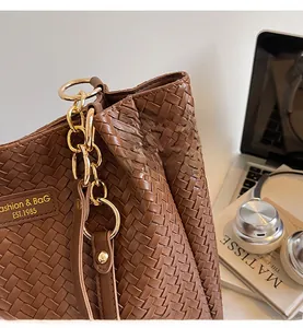 Détail de sac cabas tressé marron avec anneau doré et étiquette de marque sur bureau