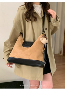 Detail of vintage suede tote bag with contrast leather trim and cute bear charm accessory