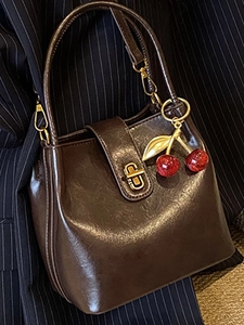 Retro dark brown bucket bag with glossy finish and cherry charm for autumn outfits