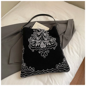 Detailed white embroidery on black suede tote bag with slim leather shoulder straps