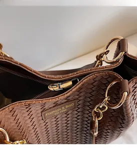 Détail d'un sac cabas marron tissé avec fermeture éclair métallique et étiquette en cuir