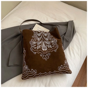 Detailed embroidery on dark brown suede tote bag with floral patterns and leather strap