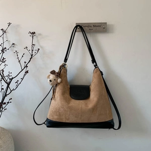 Detail of khaki suede tote bag with black leather patchwork and cute bear charm