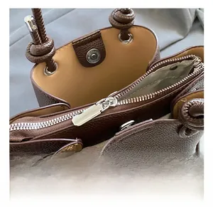 Detailed macro view of dark brown pebbled leather handbag with silver metal hardware