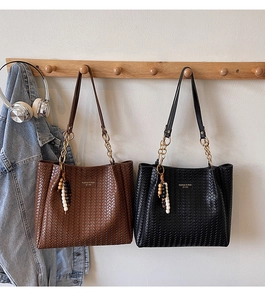 Détail des sacs fourre-tout tissés avec breloques en perles de bois et chaînes en métal