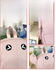 Detail view of pink twill backpack showing funny cartoon eyes design and metal zippers