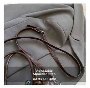 Detail of adjustable brown pebbled leather shoulder strap with sturdy metal buckle