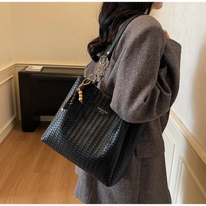 Gros plan du sac cabas tressé noir avec bandoulière en chaîne et détails de perles
