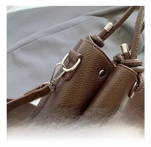 Detail of dark brown pebble leather bag showing silver metal hooks and D-ring attachments