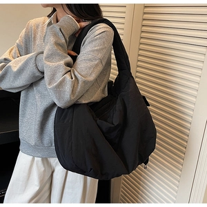 Détail d'un grand sac hobo noir en nylon avec une large bandoulière et une finition mate