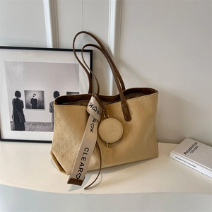 Detail of beige textured tote bag with diamond pattern and brown leather handles