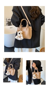 Detail view of beige lychee texture tote with plush puppy charm and adjustable strap