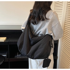 Détail d'un grand sac bandoulière en nylon noir avec une mini pochette amovible