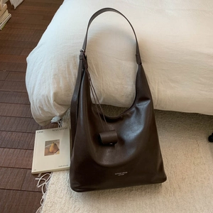 Vue détaillée du sac cabas en cuir marron foncé avec large bandoulière et logo embossé