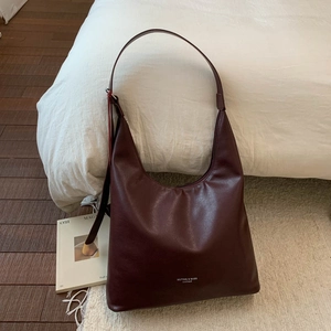 Gros plan sur un sac hobo bordeaux en cuir souple avec inscription blanche élégante