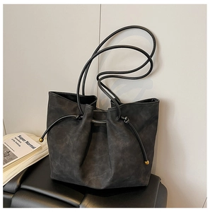 Detail of black suede bucket bag featuring drawstring closure and gold bead hardware