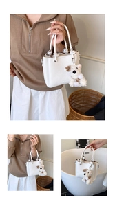 Detail view of white lychee pattern leather tote bag with woven handle and plush dog charm