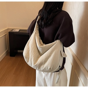 Gros plan sur un grand sac bandoulière croissant blanc cassé avec poche latérale et texture douce