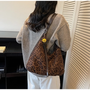 Detail of leopard print suede crossbody bag with long tassels and yellow daisy pendant