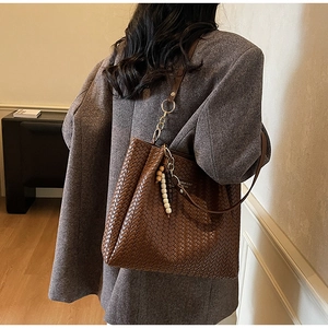 Détail du cabas en cuir tressé marron foncé avec pendentif chaîne et perles