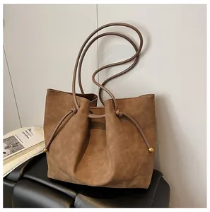 Detail of brown faux suede tote bag with gold ball drawstring and textured finish