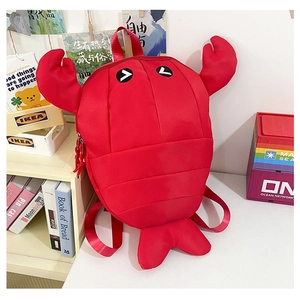 Detail of red cartoon lobster backpack with 3D claws and embroidered eyes in a lifestyle setting