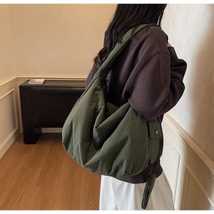 Détail du grand sac bandoulière vert foncé montrant la texture froncée et poche latérale