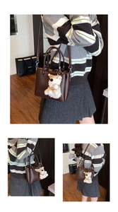 Detail of dark brown litchi pattern leather handbag with cute white plush puppy charm