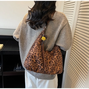 Detail view of large leopard print tote bag with stylish fringe and plush ball charm