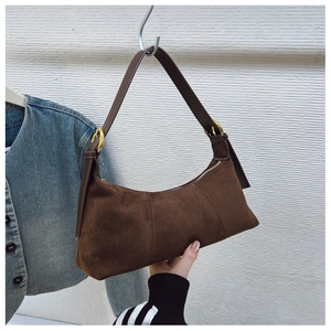 Detailed macro view of dark brown suede shoulder bag texture with golden metal buckle