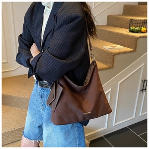 Close-up of brown suede shoulder bag with hanging pouch and golden zipper detail