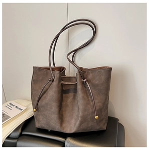Close-up of coffee brown matte leather tote bag with knot drawstring and gold bead detail