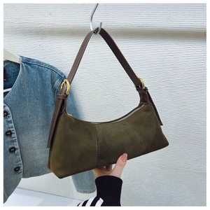 Detail view of dark green suede underarm bag with brown leather strap and gold buckle