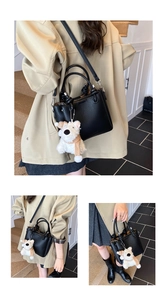 Detail of black pebbled leather bucket bag with a cute white puppy plush charm