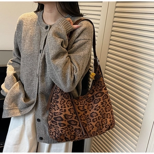 Detail of leopard print hobo bag with brown strap and yellow pompom charm on model
