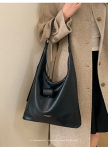 Sac hobo classique en cuir noir porté avec un grand manteau d'hiver en laine beige