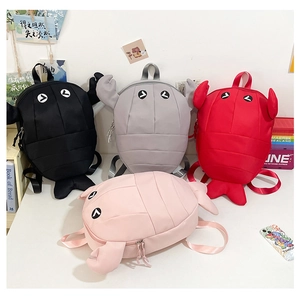 Flat lay of colorful shark backpacks in black, grey, red and pink with 3D cartoon details