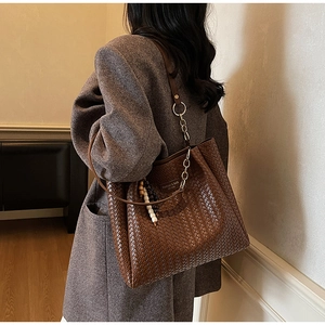Détail du sac cabas marron tressé avec bandoulière en chaîne et pendentif perlé