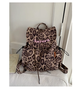 Detail of vintage leopard print canvas backpack showing pink embroidery and side drawstring