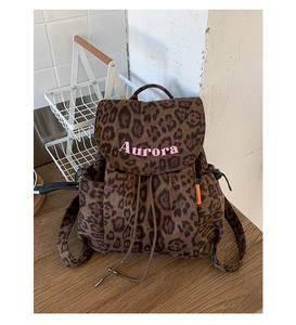 Close-up of leopard print canvas backpack with pink Aurora embroidery and side drawstring detail