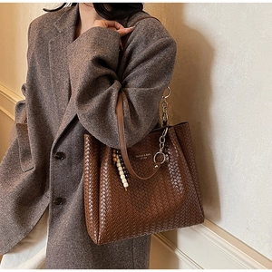 Détail d'un sac cabas marron tissé avec chaîne métallique et perles en bois décor