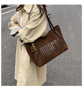 Detail of dark brown matte tote bag with embossed TOACRI logo and animal charm