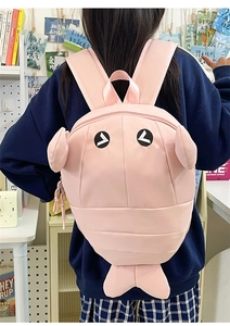 Pink cartoon shark backpack with 3D fins shown from the back of a female model