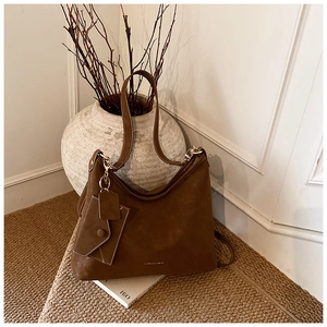 Detailed macro of dark brown frosted suede tote bag with removable envelope charm pendant