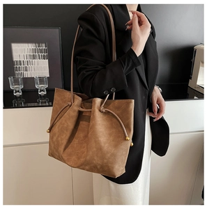 Detail view of caramel brown drawstring tote bag with gold beads on smooth faux leather